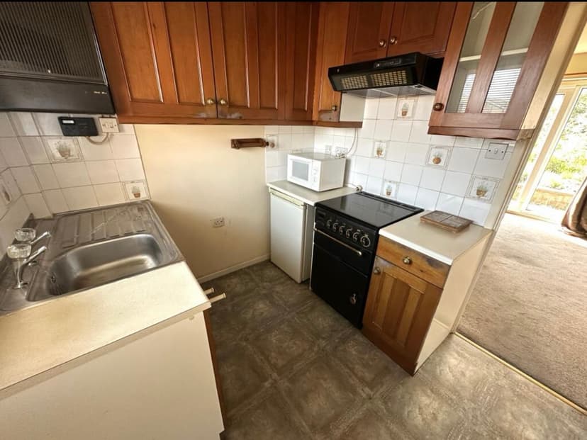 Outdated kitchen before renovation with yellow walls and basic white cabinets